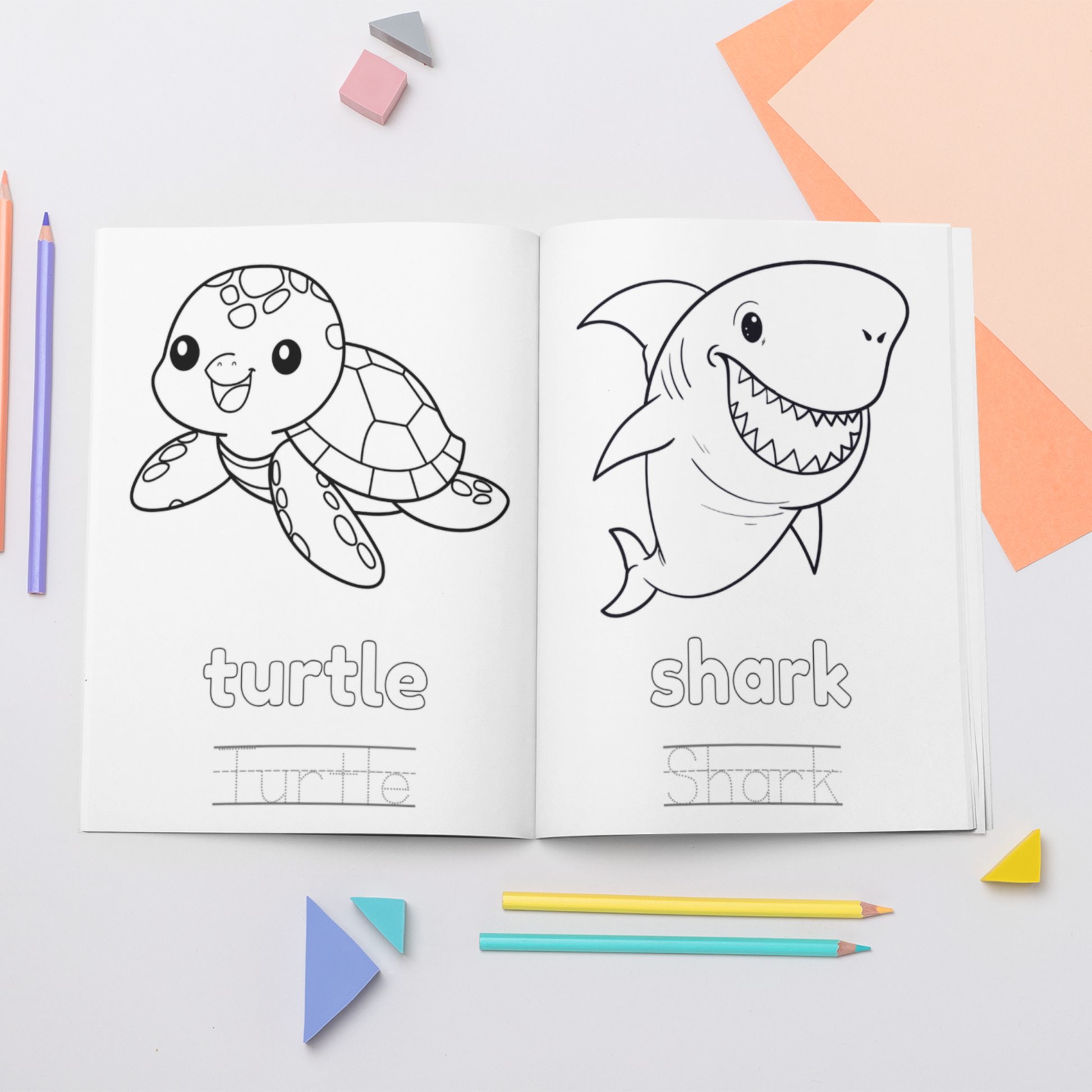 Coloring book open to pages with a turtle and shark, surrounded by coloring pencils and geometric shapes on a light background.